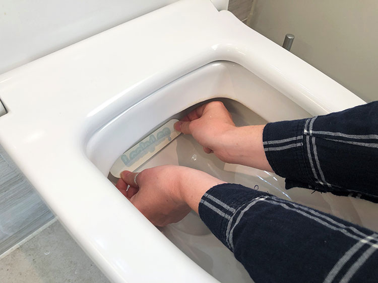 Image of a leaky loo strip being applied to a toilet rim